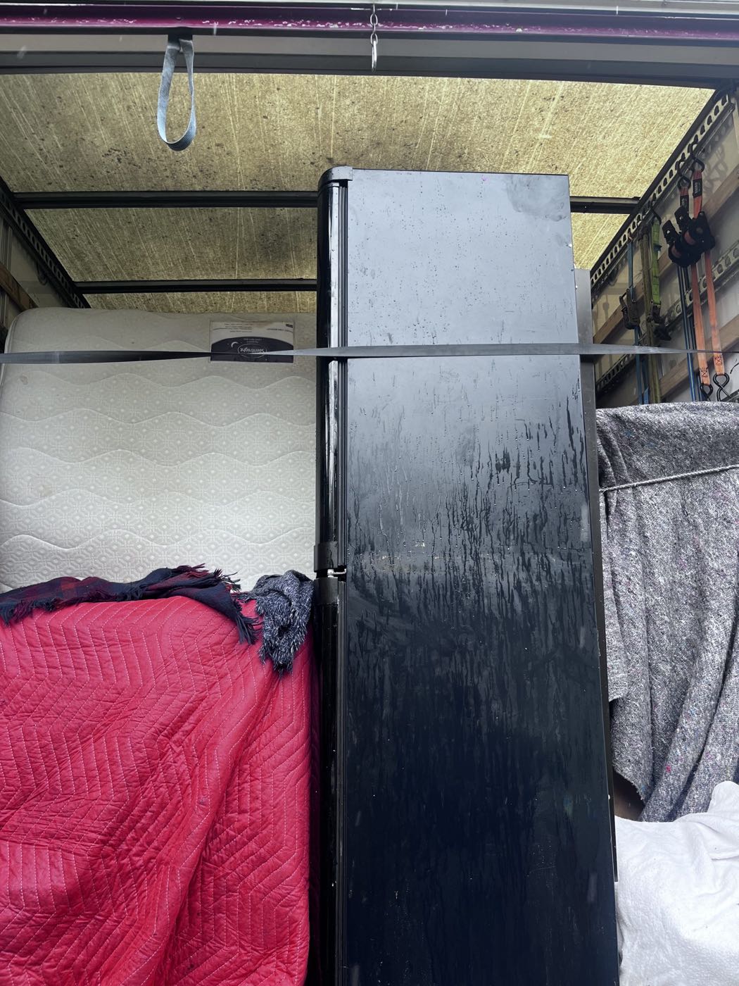 A fridge freezer wrapped in protective blankets and strapped inside the removals van